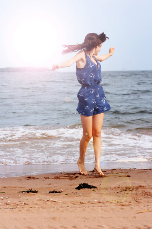 lens flare photography with girl jumping on the beach
