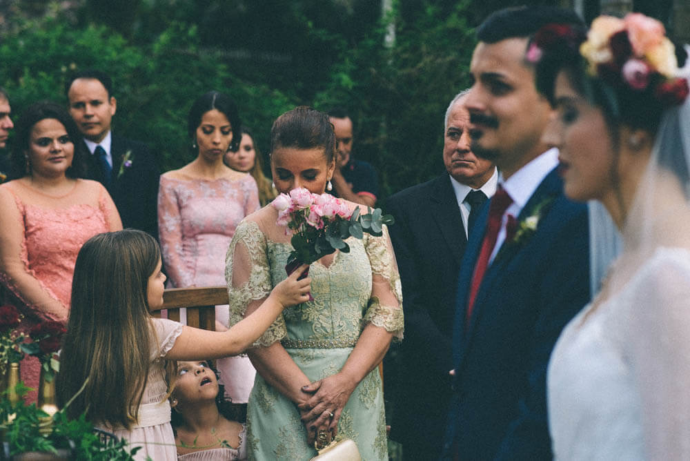Layered wedding photo with bride and groom in foreground and a girl having her mom smell flowers in the background